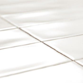 Les carreaux rectangulaires blancs sont disposés selon un motif en grille, projetant des ombres douces dues à la réflexion de la