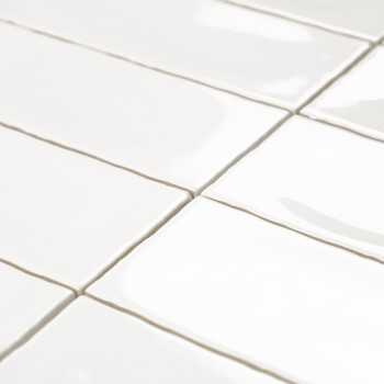 White rectangular tiles are aligned in a staggered pattern, reflecting light on a smooth, glossy surface with minimal visible gr
