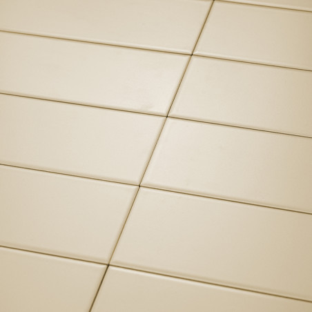 Les carreaux rectangulaires de couleur crème sont soigneusement disposés selon un motif de grille diagonale. La surface lisse re