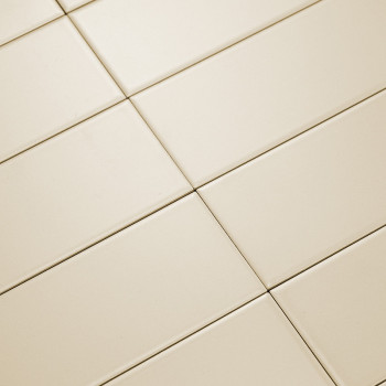Les carreaux rectangulaires de couleur crème sont posés en diagonale, formant un quadrillage. La surface lisse reflète la lumièr