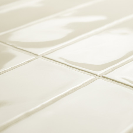 Les carreaux rectangulaires blancs brillants forment un motif en grille, reflétant la lumière dans une pièce spacieuse, avec des