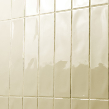 Los azulejos rectangulares y brillantes están dispuestos en forma de cuadrícula en una pared, reflejando la luz en un baño o coc