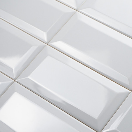 Ladrilhos retangulares brancos dispostos em grade, com superfície brilhante e chanfrada que reflete a luz em um padrão uniforme.