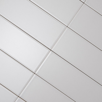 Ladrilhos retangulares brancos alinhados diagonalmente, criando um padrão de grade. Linhas escuras de rejunte separam os azulejo