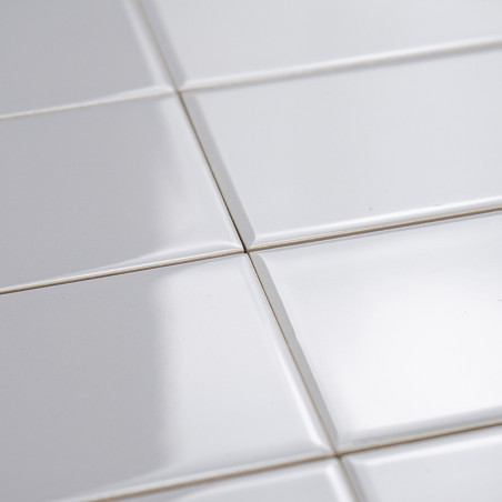 Les carreaux de céramique blancs et brillants sont plats et reflètent subtilement la lumière. Ils sont disposés selon un motif e