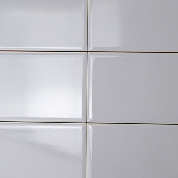Los azulejos rectangulares blancos están alineados en un patrón de cuadrícula, creando una superficie lisa y brillante bajo una 
