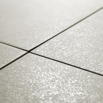 Ceramic tiles, arranged in a grid pattern, are aligned on a flat surface. The tiles have a subtle, textured finish.