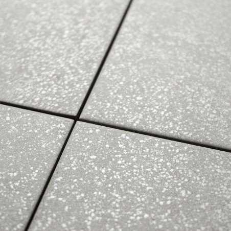 Gray square tiles display a subtle speckled pattern, creating a textured surface. They are arranged in a grid, forming an orderl