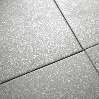 Gray, speckled tiles are arranged in a grid, forming a seamless surface with subtle white specks, suggesting a modern, minimalis