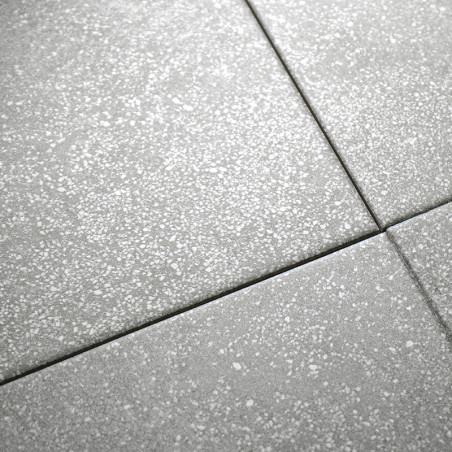 Los azulejos grises y moteados están dispuestos en una cuadrícula, formando una superficie perfecta con sutiles motas blancas, l