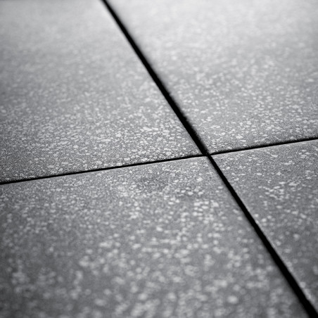 Gray ceramic tiles intersect, forming a grid pattern. Each tile is speckled with a light texture, creating a subtle contrast.