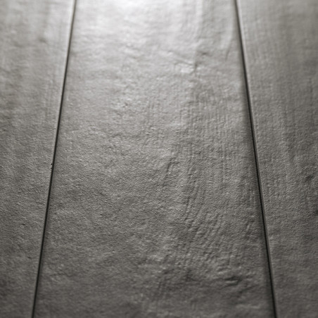 Graue rechteckige Fliesen liegen flach mit einer dezent strukturierten Oberfläche, reflektieren Licht und ähneln einem Holzboden