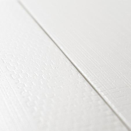 Twee witte getextureerde tegels met subtiele patronen ontmoeten elkaar in een naad, waardoor een minimalistisch ontwerp ontstaat