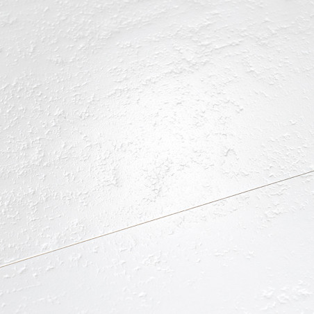 Un carrelage blanc mat et lisse repose sur un sol, subtilement texturé avec un motif sporadique de petites bosses en relief.