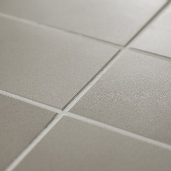 Matte quadratische Fliesen bilden ein Gittermuster, das bei sanfter Beleuchtung im Innenbereich einheitlich und ordentlich wirkt