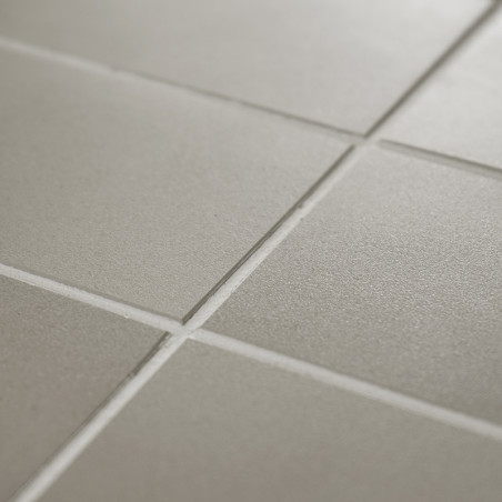 Los azulejos cuadrados mate forman un patrón de cuadrícula, que parece uniforme y ordenado, con una textura sutil bajo una ilumi