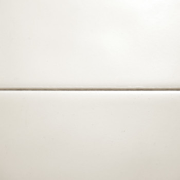 Deux carreaux blancs unis, séparés par une fine ligne de coulis horizontale, forment une surface simple et propre sur un fond ne