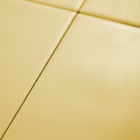 Four smooth, yellow tiles form a grid, creating a minimalist geometric pattern on a flat surface.