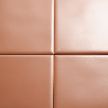 Quatre carreaux beiges et lisses se croisent pour former un motif en croix. la surface est brillante, suggérant un environnement