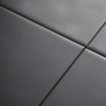 Quatro ladrilhos cerâmicos lisos e cinza escuro estão alinhados em um padrão de grade, formando uma superfície moderna e perfeit