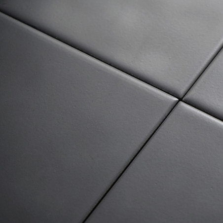Cuatro azulejos cerámicos lisas de color gris oscuro están alineadas en un patrón de cuadrícula, formando una superficie moderna