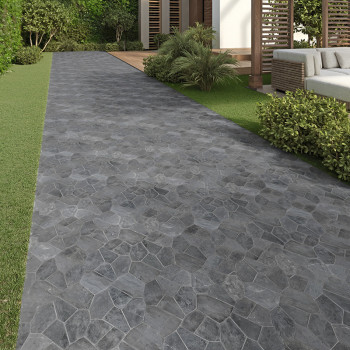 Los azulejos de piedra gris forman un camino que atraviesa un jardín con arbustos verdes y un patio moderno.