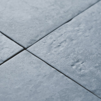 Quatro ladrilhos cinza semelhantes a pedra formam um padrão com texturas sutis e leves recortes, criando uma superfície lisa e u