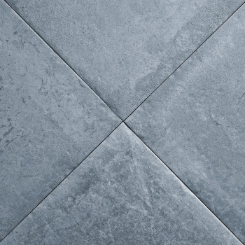 Quatro ladrilhos cinza escuro formam um padrão X com marmoreio sutil, criando uma superfície texturizada em um ambiente neutro e