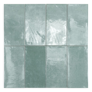 Le carreau de céramique rectangulaire avec une surface verte brillante reflète légèrement la lumière. Il repose sur un fond uni 