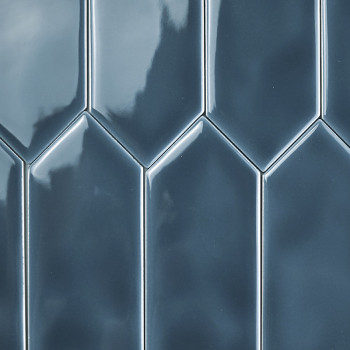 Glänzende, blaue Fliesen bilden vertikal angeordnet ein gestaffeltes, geometrisches Muster. Die Oberfläche reflektiert das Licht