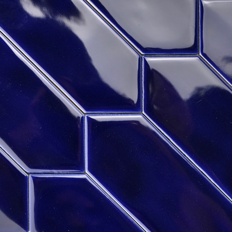Glänzende, dunkelblau glasierte Fliesen bilden ein geometrisches Muster mit diagonalen Linien und abgewinkelten Rechtecken und r