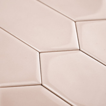 Les carreaux beiges hexagonaux s'emboîtent parfaitement, créant un motif géométrique. La surface lisse et brillante reflète subt