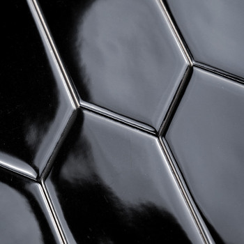 Les carreaux de céramique noirs lisses et brillants, disposés selon un motif hexagonal répétitif, reflètent la lumière dans un e