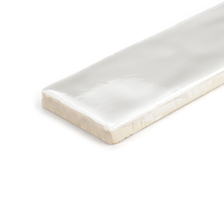 Un carreau blanc brillant et rectangulaire repose à plat sur une surface blanche, avec des bords biseautés et une finition lisse