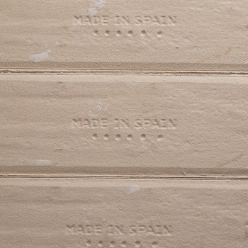 Der geprägte Text „MADE IN SPAIN“ erscheint auf den beigefarbenen Fliesenkanten, mit kleinen Punkten unter jedem Satz, die den H