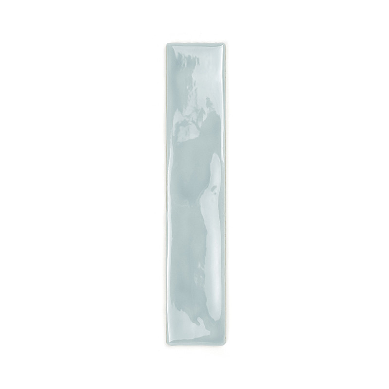 Un azulejo cerámico larga y rectangular está esmaltada en un color azul pálido brillante que refleja la luz. Se apoya sobre un f