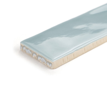 Un carreau de céramique rectangulaire à la surface bleu clair brillante repose sur un fond blanc uni, affichant sa finition liss