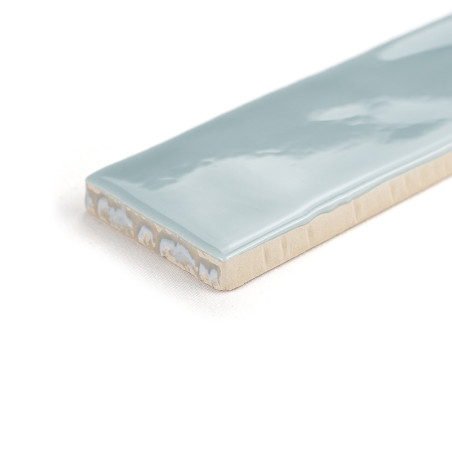 Um revestimento cerâmico retangular com superfície azul claro brilhante repousa sobre um fundo branco liso, exibindo seu acabame