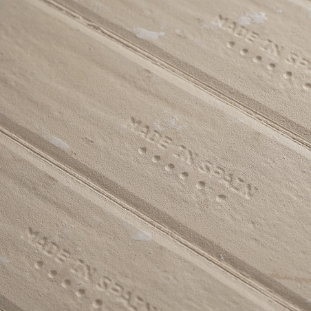 Geprägte beige Keramikfliesen mit der Aufschrift „MADE IN SPAIN“ liegen in horizontaler Ausrichtung und sind mit dezenten, unreg