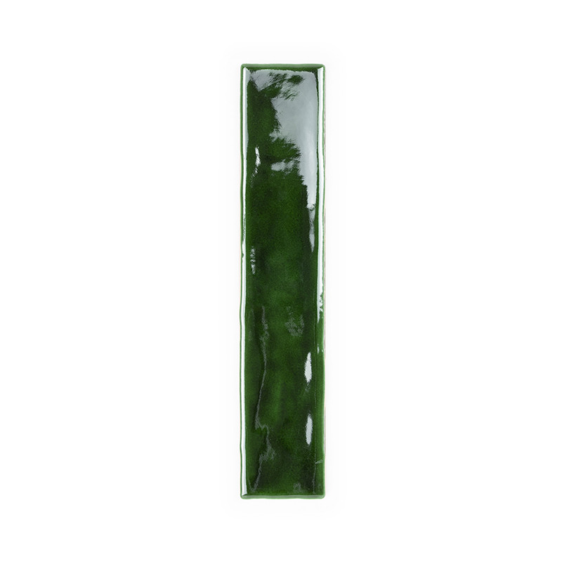 Un long carreau vert rectangulaire et brillant repose sur un fond blanc uni, sa surface réfléchissante mettant en valeur de subt