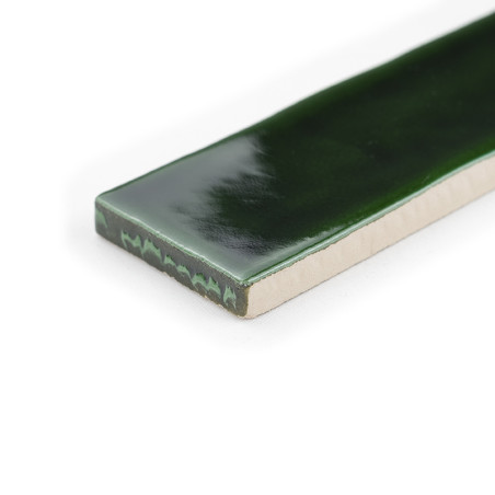 Un azulejo rectangular presenta una superficie brillante de color verde oscuro, que refleja la luz sutilmente, sobre un fondo bl