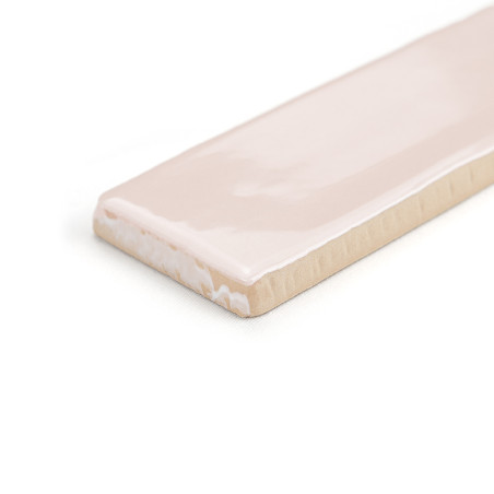 Un carreau de céramique rectangulaire présente une surface brillante rose clair avec un bord biseauté, sur un fond blanc uni.