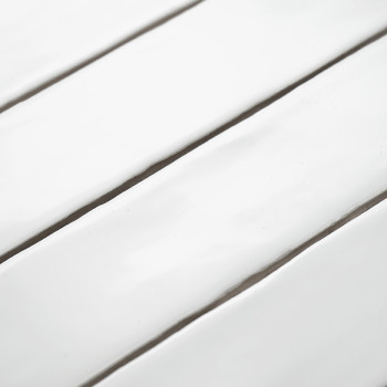 Witte keramische tegels liggen parallel en reflecteren licht, waardoor een glanzend en strak beeld ontstaat in een vloeiende, ge