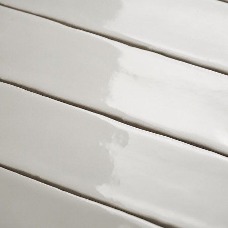 Los azulejos rectangulares brillantes se colocan en un patrón escalonado, reflejando la luz suavemente sobre una superficie lisa