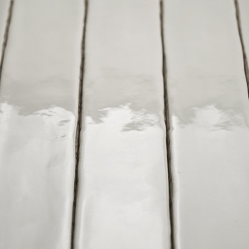 Les carreaux rectangulaires blancs brillants s'alignent verticalement, reflétant une lumière douce. Ils sont séparés par de fine