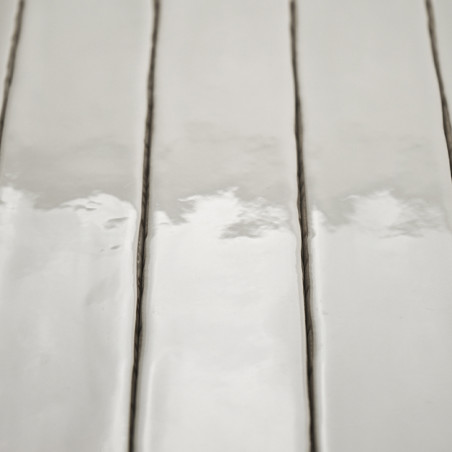 Los azulejos rectangulares de color blanco brillante se alinean verticalmente y reflejan una luz suave. Están separados por líne