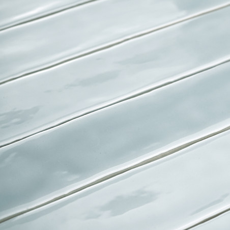 Des carreaux gris clair brillants et allongés sont disposés parallèlement à des arêtes subtiles, créant une surface propre et mo