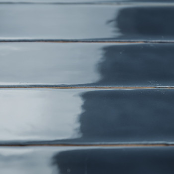 Los azulejos rectangulares brillantes están alineados horizontalmente con una superficie reflectante de color azul oscuro, lo qu