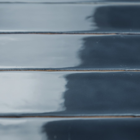 Glanzende, rechthoekige tegels zijn horizontaal uitgelijnd met een reflecterend donkerblauw oppervlak, wat een strak, modern int