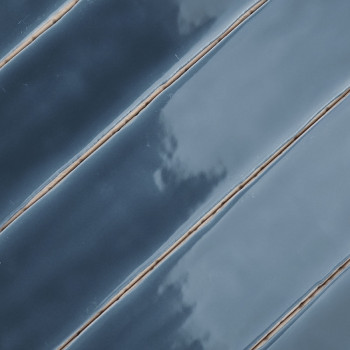azulejos de cerámica azul alineadas en diagonal con acabado brillante, reflejando la luz, separadas por finas líneas de lechada 